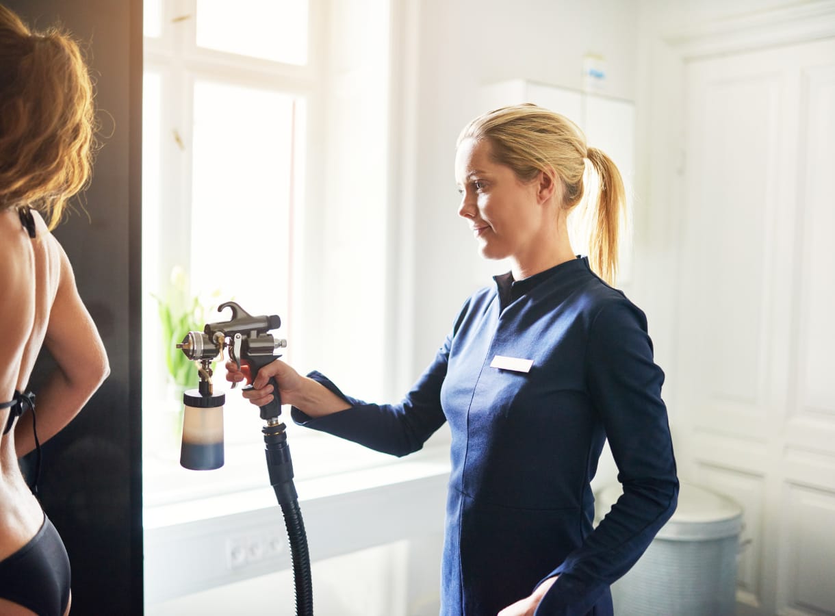 Beautician giving client a spray tan